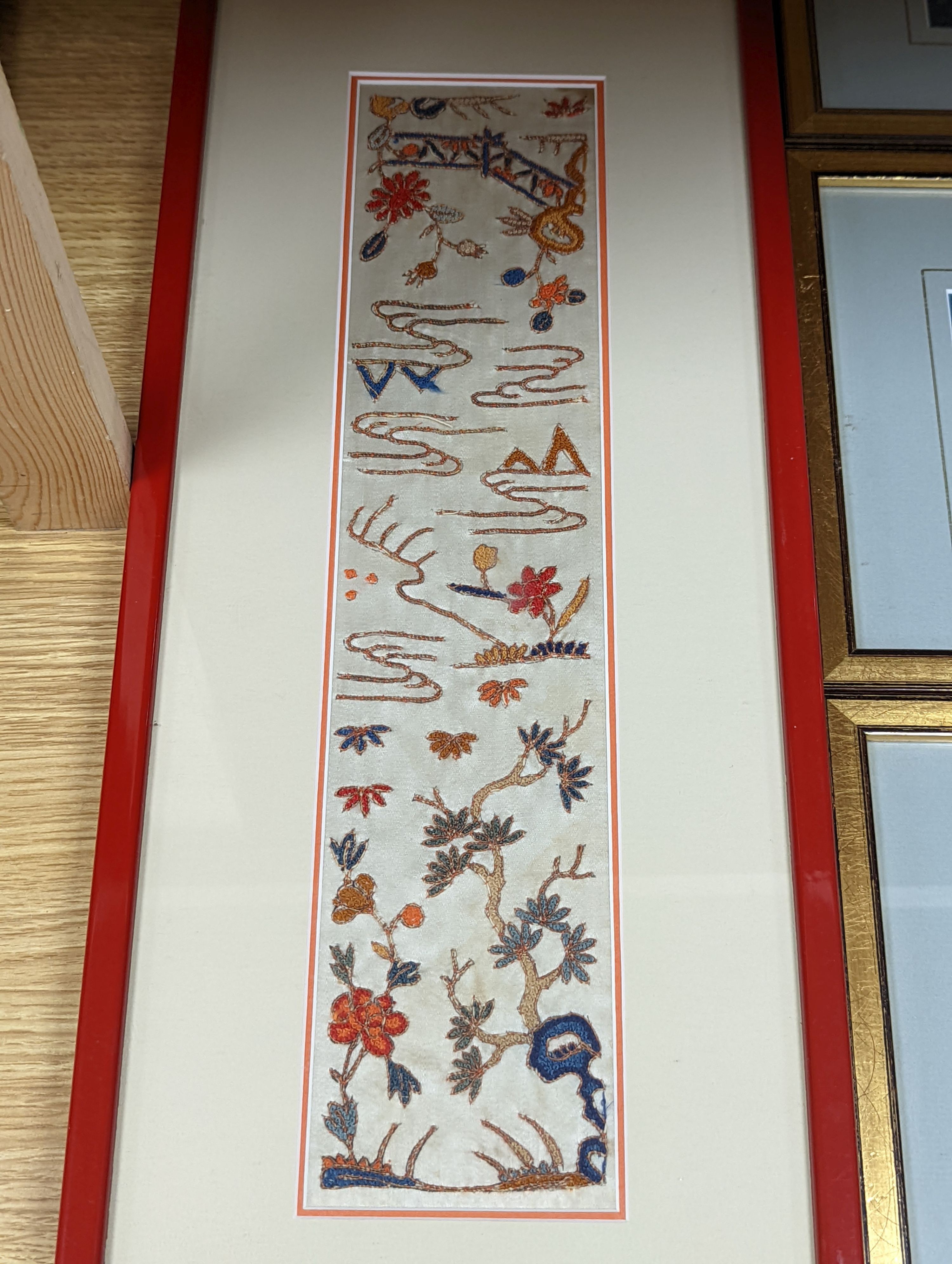 A set of four Chinese silk embroidered motifs, a pair of floral silk motifs and a later pair f sleeve bands, all framed